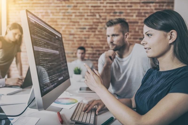 probetag Eine Frau zeigt auf ihren Bildschirm mit Code-Zeilen